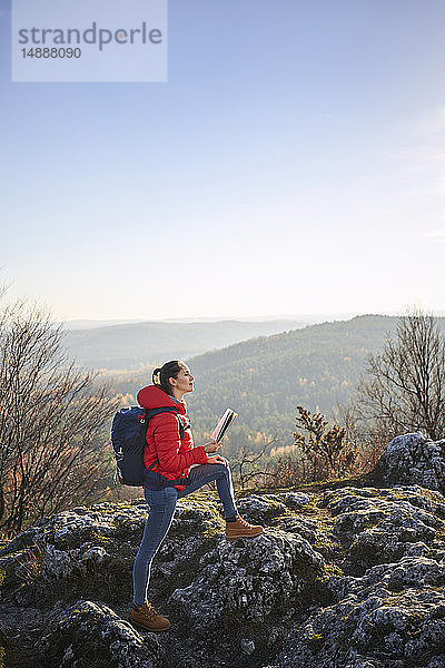 Frau auf einer Wanderung in den Bergen mit Karte in der Hand und schöner Aussicht