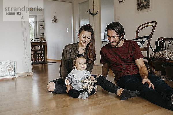 Glückliche Familie mit einem kleinen Mädchen  das zu Hause auf dem Boden sitzt