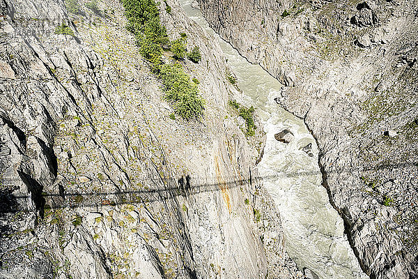 Schweiz  Wallis  Schatten von zwei Personen auf einer schwingenden Brücke über einer Schlucht
