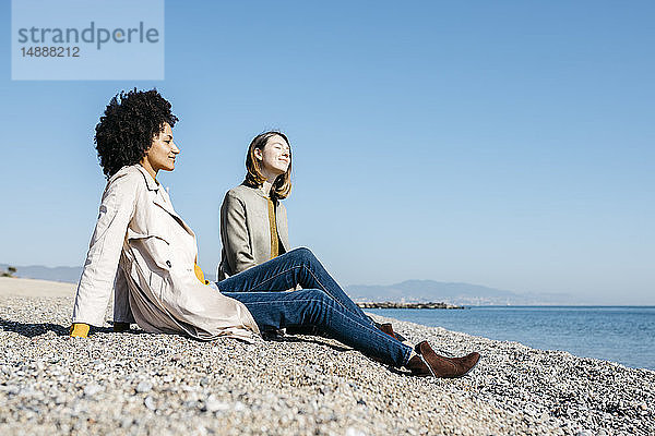 Zwei Freunde sitzen am Strand und genießen ihre Freizeit