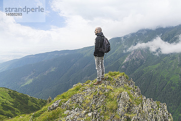 Mann  der auf einem Hügel steht und auf die Landschaft in den Karpaten schaut  Rumänien