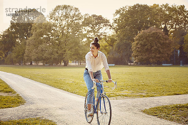 Junge Frau fährt Fahrrad in einem Park