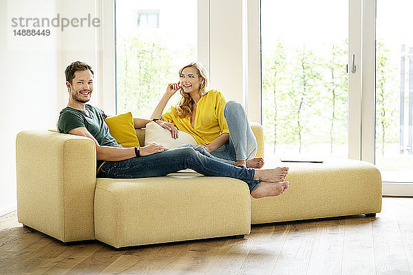 Paar sitzt in seinem neuen Zuhause auf der Couch und diskutiert