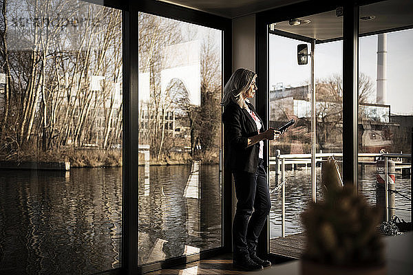 Geschäftsfrau  die auf einem Hausboot steht und ein digitales Tabet verwendet