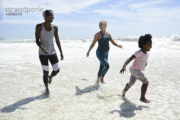 Mutter mit Tochter und Freundin haben Spaß beim Surfen am Strand