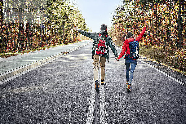 Glückliches Paar geht mitten auf einer leeren Straße im Wald