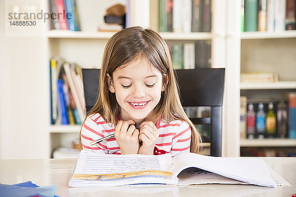Porträt eines glücklichen kleinen Mädchens bei den Hausaufgaben