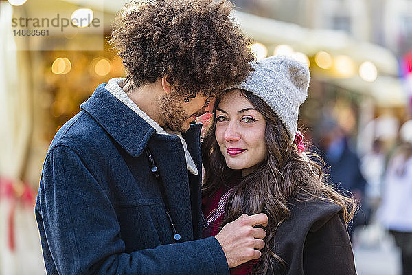 Glückliches  liebevolles junges Paar auf dem Weihnachtsmarkt