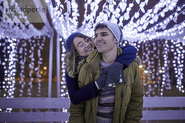 Glückliches junges Paar umarmt sich in winterlicher Dekoration