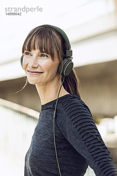 Sportliche Frau mit Kopfhörern  die ihr Fitnesstraining im Freien absolviert