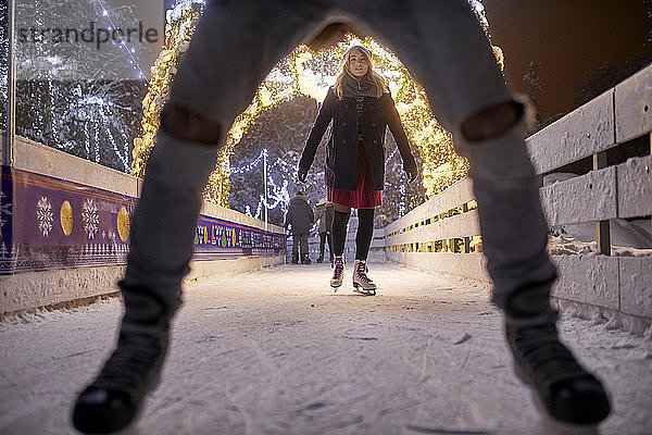 Junge Frau läuft nachts auf einer Eisbahn Schlittschuh
