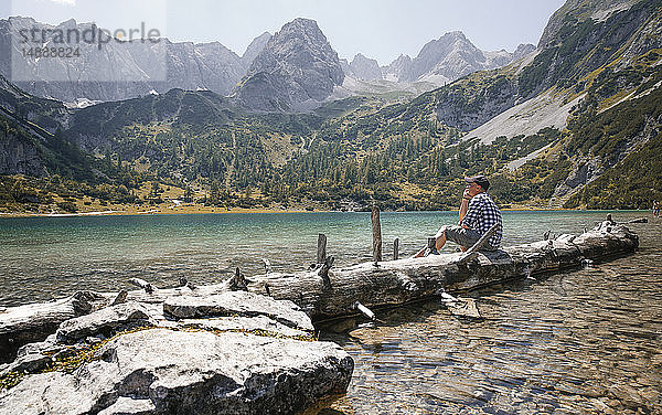 Österreich  Tirol  Mann auf Baumstamm am Seebensee sitzend