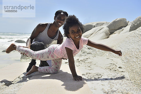 Mutter und Tochter bei einer Gymnastikübung am Strand