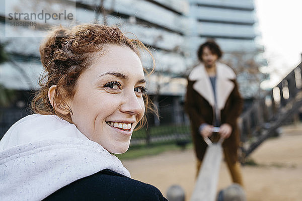 Porträt einer glücklichen jungen Frau mit Freund auf einer Wippe auf einem Spielplatz