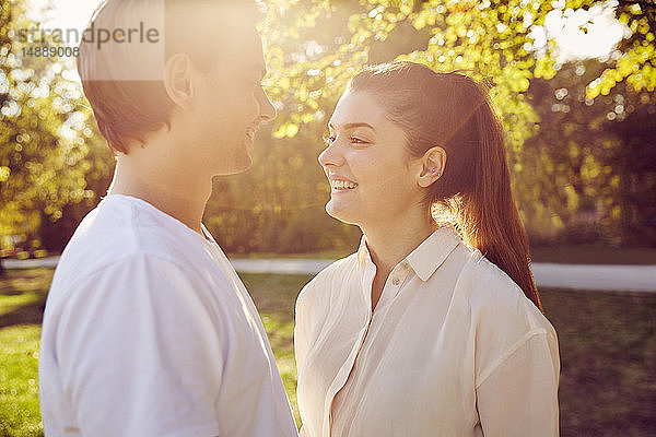 Junges Paar lächelt sich bei Sonnenuntergang in einem Park an