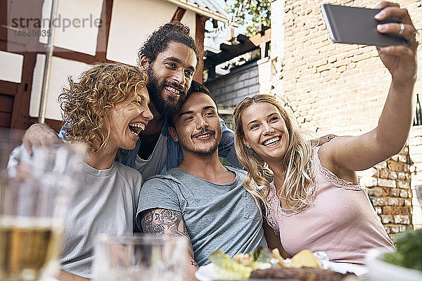 Freunde amüsieren sich auf einer Grillparty und fotografieren mit ihren Smartphones