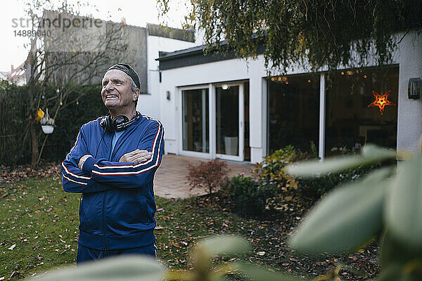 Glücklicher sportlicher älterer Mann im Trainingsanzug steht im Garten