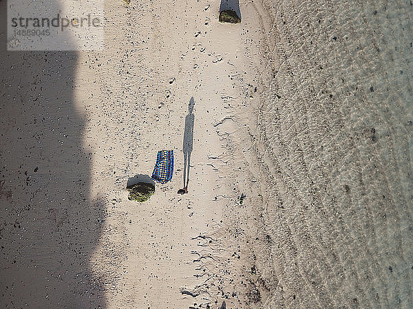 Schatten einer am Strand stehenden Frau  Draufsicht
