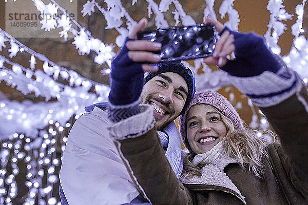 Glückliches junges Paar in Winterdekoration beim Selbermachen