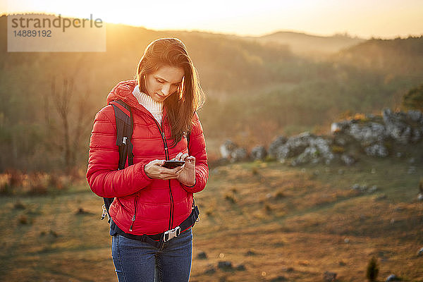 Frau auf einer Wanderung in den Bergen mit dem Handy