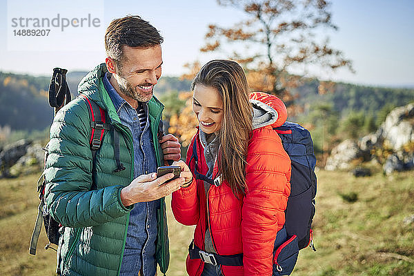 Glückliches Paar auf einer Wanderung in den Bergen beim Handy-Check