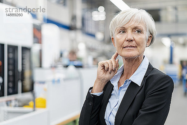 Porträt einer älteren Geschäftsfrau in einer Fabrik  die sich umsieht