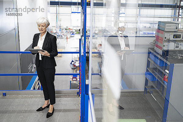 Leitende Geschäftsfrau mit Tabletten in einer Fabrik