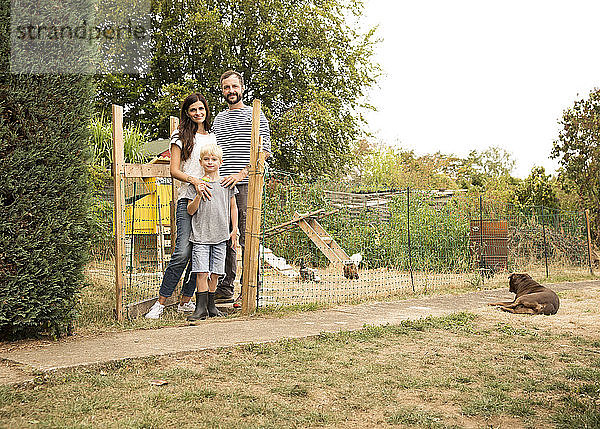 Porträt einer selbstbewussten Familie  die im Hühnerstall im Garten steht