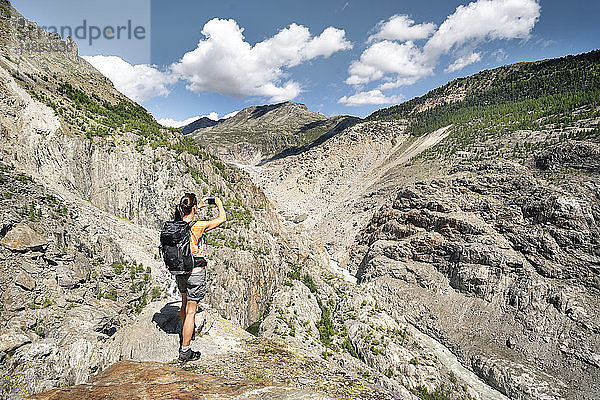 Schweiz  Wallis  Frau beim Fotografieren während einer Wanderung in den Bergen am Aletschgletscher