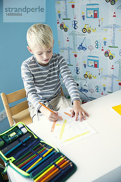 Junge malt auf Papier am Schreibtisch im Kinderzimmer