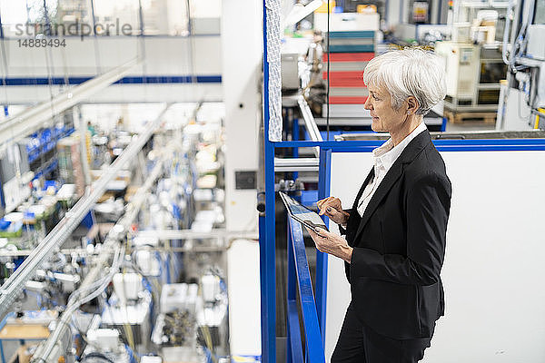 Leitende Geschäftsfrau mit Tabletten in einer Fabrik