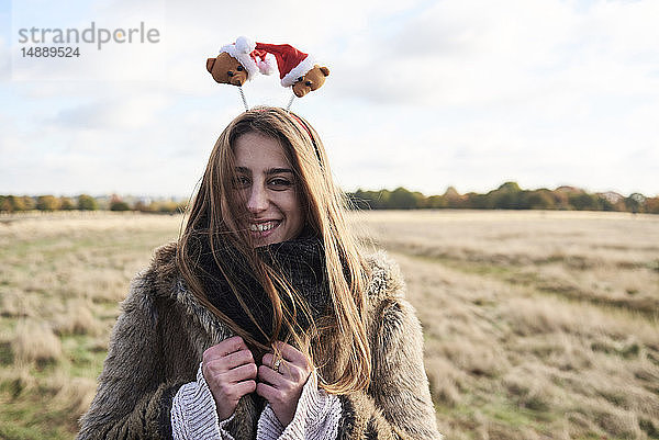 Porträt einer glücklichen jungen Frau mit weihnachtlichem Kopfschmuck auf dem Land
