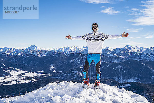 Deutschland  Bayern  Brauneck  glücklicher Mann im Winter auf dem Berggipfel stehend