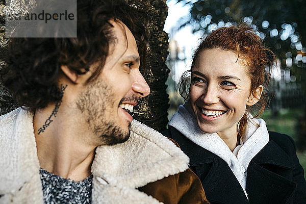 Porträt eines glücklichen Paares an einem Baumstamm im Park