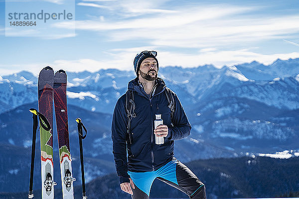 Deutschland  Bayern  Brauneck  Mann auf Skitour im Winter in den Bergen bei einer Pause