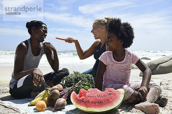 Mutter mit Tochter und Freundin beim Picknick am Strand