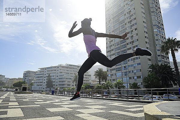 Sportliche Frau springt im Freien