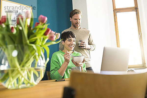 Glückliches Paar schaut sich Laptop im Heimbüro an