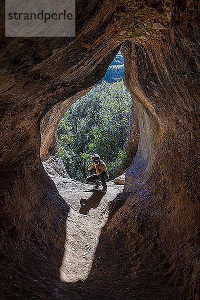 Junger Mann beim Fotografieren im Höhleneingang  Cova Simanya Barcelona  Spanien
