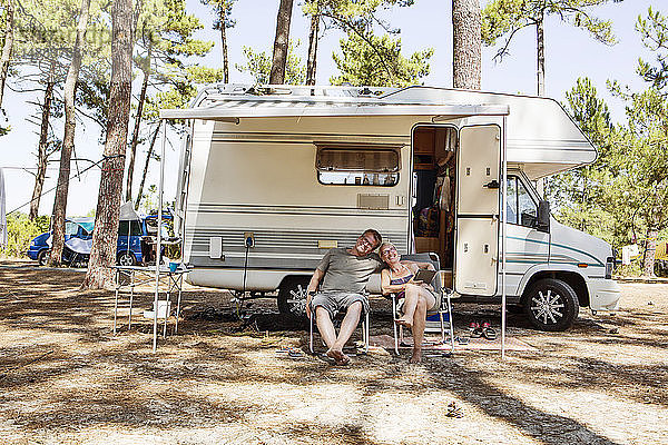 Frankreich  Gironde  glückliches Paar sitzt vor dem Wohnmobil auf dem Campingplatz