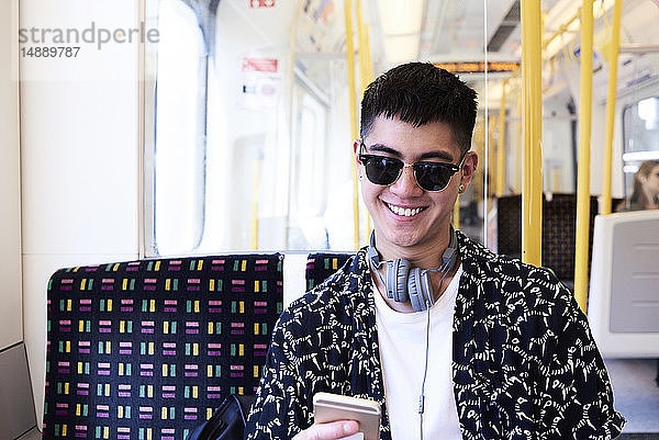 Junger Mann benutzt Smartphone im Zug