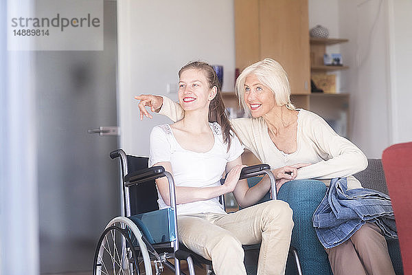 Mutter mit Tochter im Rollstuhl  zeigt mit dem Finger