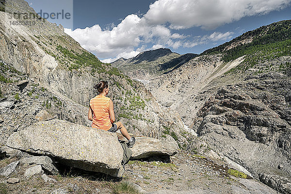 Schweiz  Wallis  Frau ruht sich während einer Wanderung in den Bergen am Aletschgletscher aus