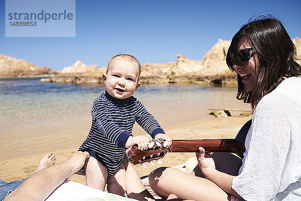 Spanien  Menorca  Porträt eines lächelnden kleinen Jungen mit Eltern am Strand