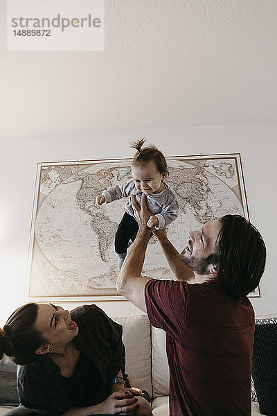 Fröhliche Familie spielt mit dem kleinen Mädchen zu Hause im Wohnzimmer