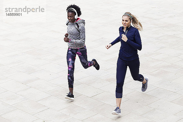 Zwei sportliche junge Frauen laufen gemeinsam in der Stadt