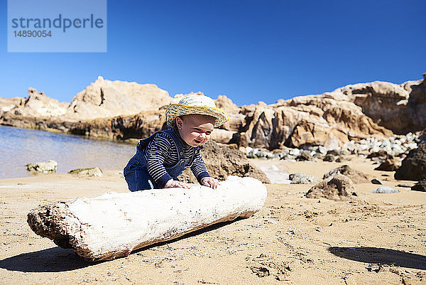 Spanien  Menorca  Kleinkind spielt mit Totholz am Strand
