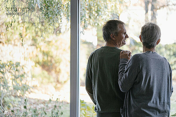 Älteres Ehepaar am Panoramafenster stehend