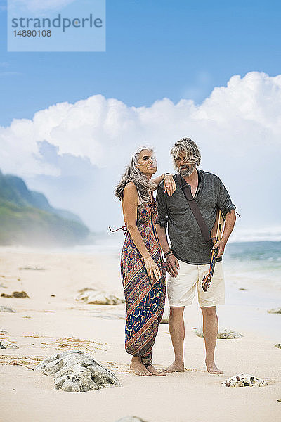 Älteres Hippie-Paar mit Gitarre am Strand stehend