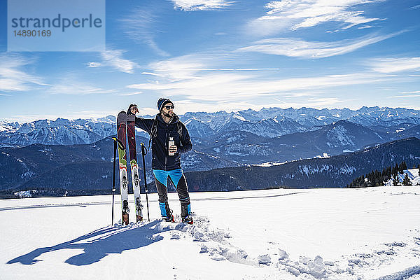 Deutschland  Bayern  Brauneck  Mann auf Skitour im Winter in den Bergen bei einer Pause